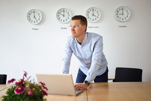 Сотрудник компании Venti Oelde перед часами с четырьмя часовыми поясами как символом "интернациональности" охранного ограждения